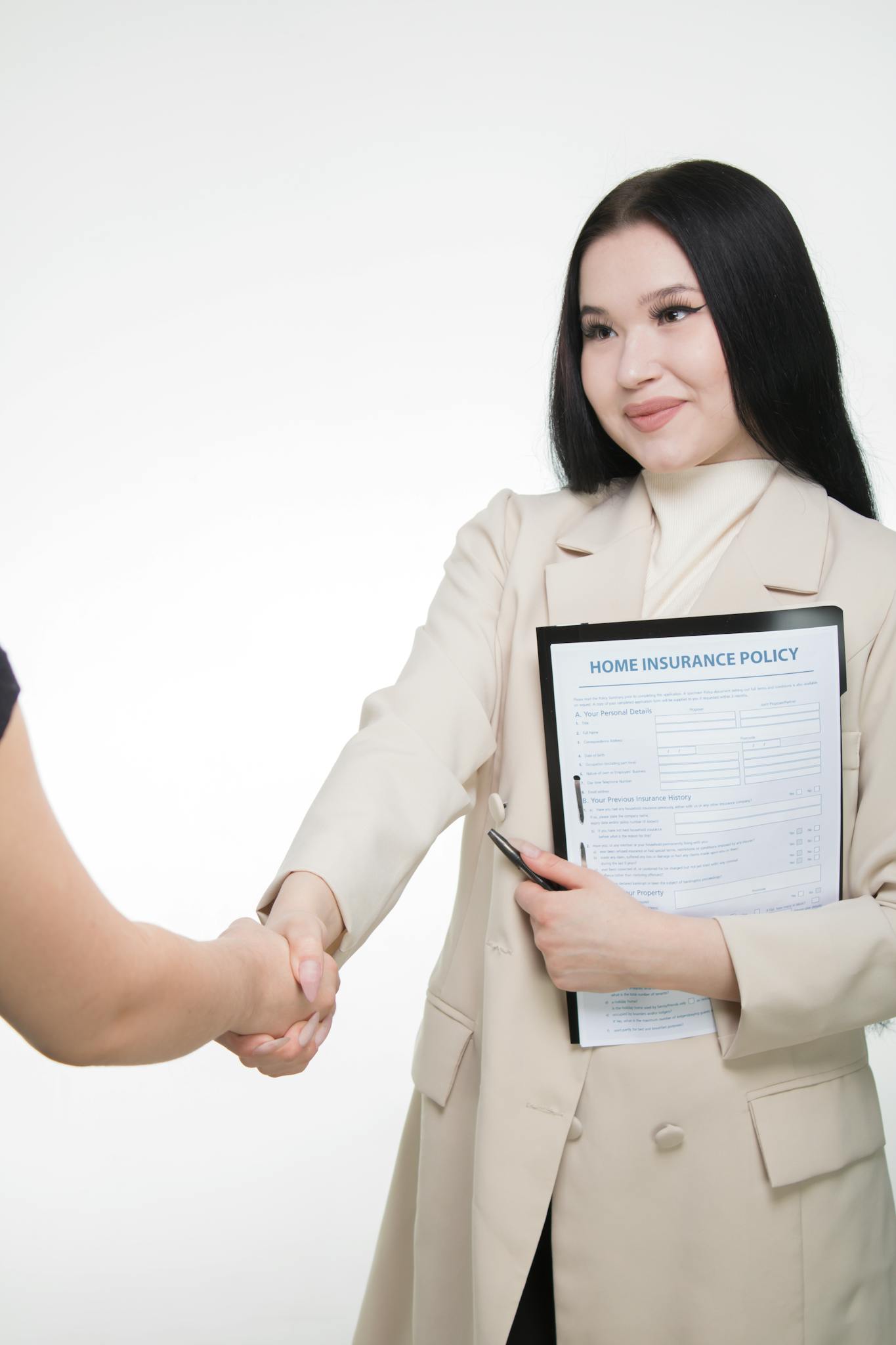 Asian woman in office attire shaking hands, holding home insurance policy document.